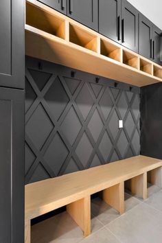 a wooden bench sitting in front of a wall with cabinets on it's sides