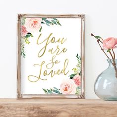 there is a vase with flowers in it next to a sign that says you are so loved