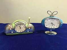 two clocks sitting on top of a blue table