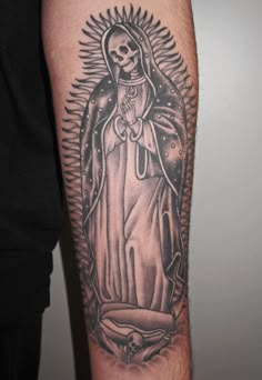 a man's arm with a black and white tattoo of a virgin mary on it