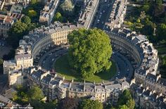 an aerial view of a circular building in the middle of a city with lots of trees