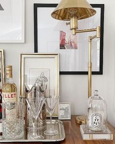 a wooden table topped with bottles and glasses on top of it next to a lamp