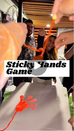 a group of people standing around a table with orange sticks sticking out of it's hands