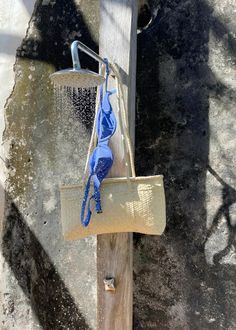 a blue bag hanging from a wooden pole on the side of a building with water coming out of it