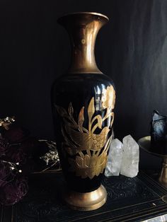 a black and gold vase sitting on top of a table next to crystal rocks in front of it