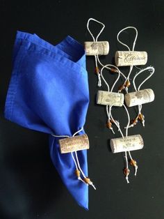 four wine corks are tied to a blue napkin and some beads hang from them