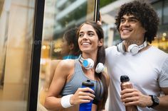 a man and woman standing next to each other in front of a window with headphones on