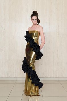 a woman in a gold dress with black ruffles