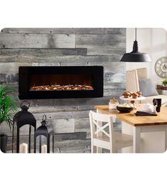 an electric fireplace in a living room next to a table with food and candles on it