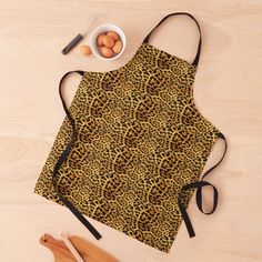 an animal print apron next to eggs and wooden utensils on top of a table