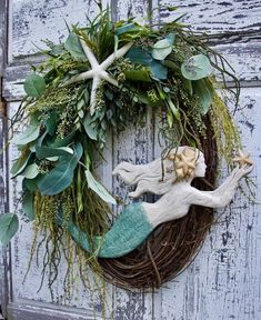 a wreath with an angel and starfish is hanging on the front door to decorate it