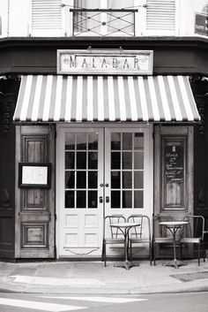 a black and white photo of a restaurant with awnings on the front door