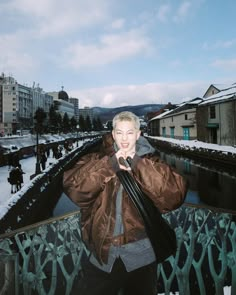 a man is standing on a bridge in the snow and talking on his cell phone