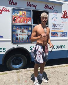 a shirtless man standing in front of a food truck holding an ice cream cone