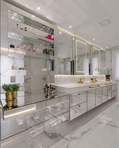 a bathroom with white marble counter tops and large mirrors on the wall, along with clear acrylic chairs