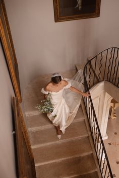 a woman in a white dress is walking down the stairs