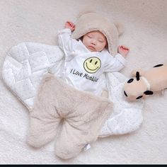 a baby laying on top of a white blanket next to a stuffed animal and pillow