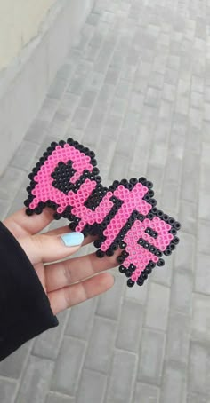 someone holding up a pink and black cross stitched sticker