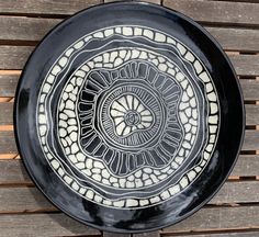 a black and white plate sitting on top of a wooden table next to a wall