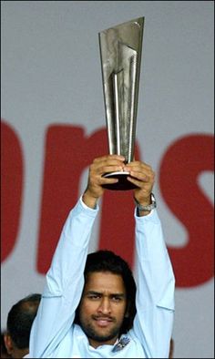 a man holding up a silver trophy in front of him with both hands and the other hand above his head