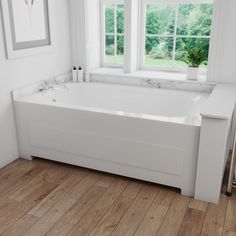 a large white bath tub sitting next to two windows in a room with wooden floors