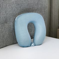 a blue pillow sitting on top of a white bed next to a gray headboard