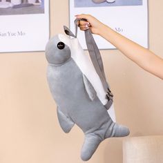 a person holding a stuffed animal in the shape of a seal with its mouth open