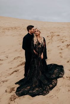 a man and woman standing on top of a sandy beach next to eachother