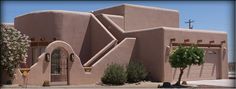 an adobe - style house in the desert with trees and bushes