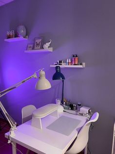 a room with purple lighting and a white desk in the corner, along with shelves on the wall