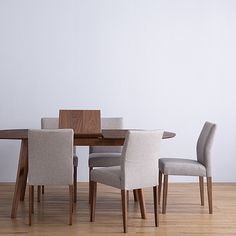 a dining room table with four chairs and a white wall in the backround