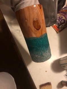 a wooden cup with blue and green glitter on it sitting on top of a counter