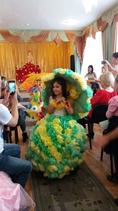 a woman in a green and yellow dress is taking a photo with her cell phone