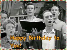 a group of people singing in front of a happy birthday card with the words, happy birthday to you