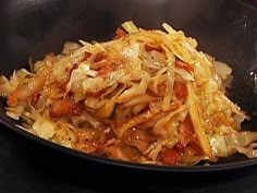 a black bowl filled with sauerkraut on top of a table