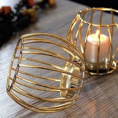 a candle that is inside of a wire basket on a table next to another one