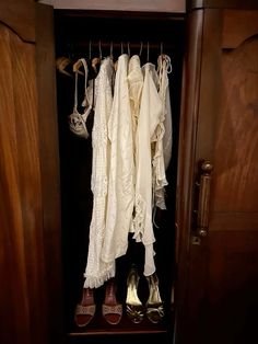 an open closet with shoes and dresses hanging on hooks