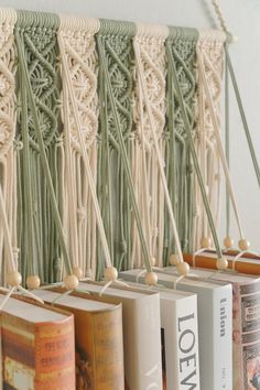 books are lined up on the wall with string and tassels attached to them