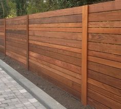 a wooden fence next to a brick walkway