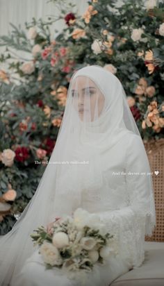 a woman wearing a veil sitting in front of flowers