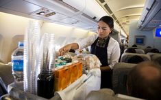 a woman is serving drinks on an airplane