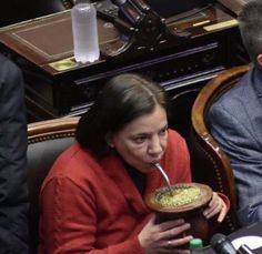 a woman sitting in a chair drinking from a straw