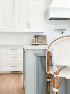 a chair sitting on top of a wooden floor next to a kitchen counter with white cabinets