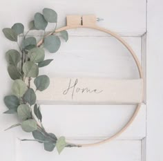 a wreath with the word home written on it and some green leaves hanging from it