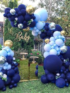 a blue and gold balloon arch for a baby's first birthday party in the backyard