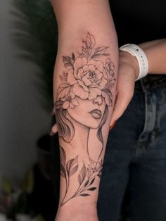 a woman's arm with a flower tattoo on her left forearm and the other hand