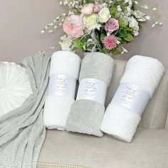 towels and flowers sit on a couch next to a vase with white flowers in it