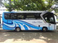 a blue and white bus parked in front of a tree