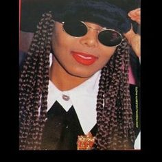 a woman with long braids wearing sunglasses and a hat