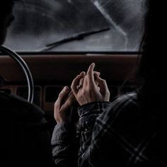 a woman sitting in the back seat of a car holding her hands up to her face